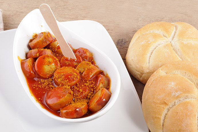 Currywurst mit Brötchen in weißer Schale