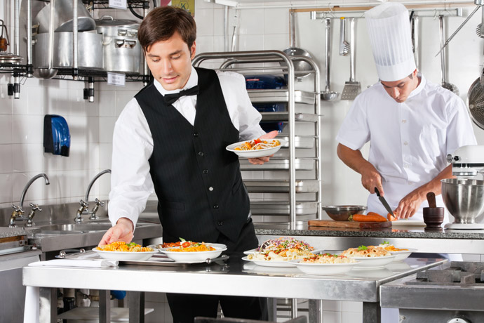 Koch und Servicekraft bei der Arbeit in Gastronomie und Hotellerie