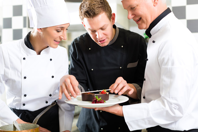 Chefkoch zeigt Kollegen, wie man das Dessert anrichtet