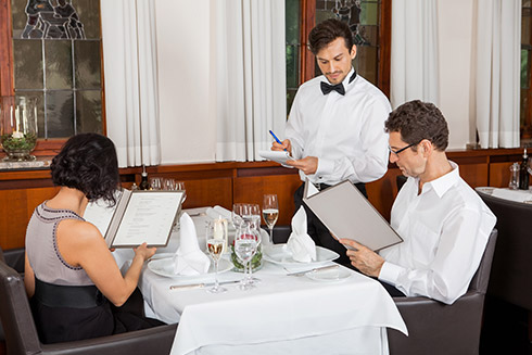 Kellner am Tisch im Hotelrestaurant mit Ehepaar