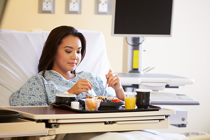 Patientin isst Krankenhausessen mit frischem Obst