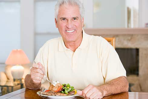 Ein Senior genießt seine Mahlzeit im Seniorenheim