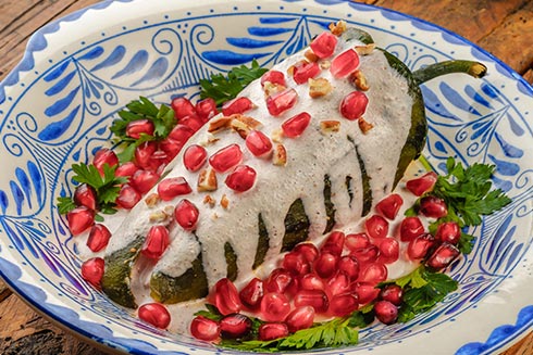 Chiles en nogada sind gefüllte, grüne Paprika mit Walnuss-Sauce und Granatapfelkernen