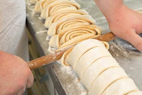 Mit Hilfe eines Kochlöffels werden Franzbrötchen vor dem Backen  speziell gequetscht 