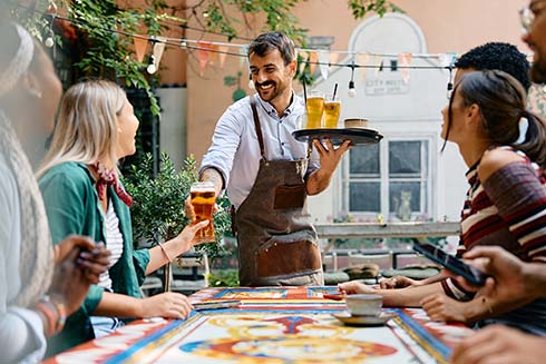 CHEFS CULINAR Kellner bedient Aussentisch auf der Restaurant-Terasse 