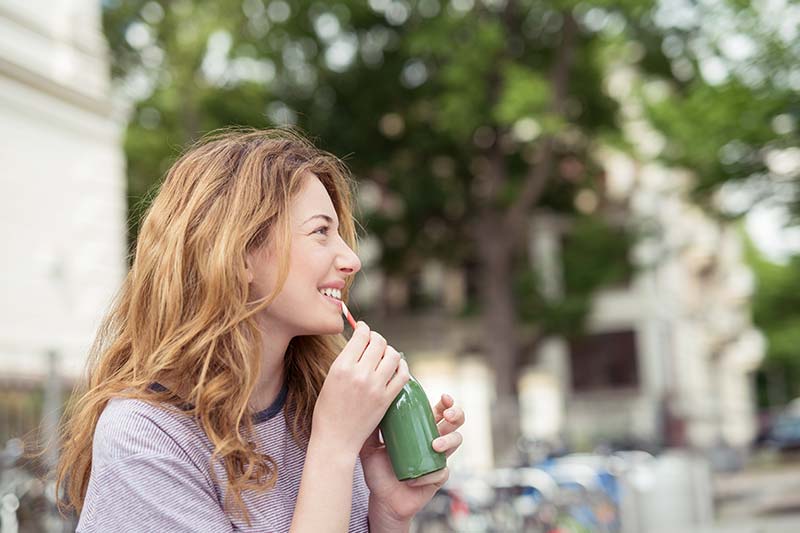 Frau trinkt grünen Smoothie in der Stadt