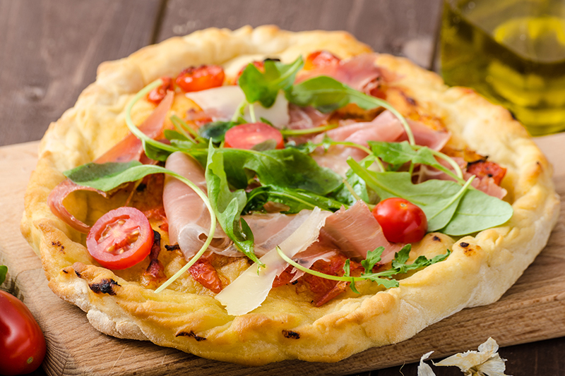 Pizza bianca mit Rucola, Schinken und frischen Tomaten