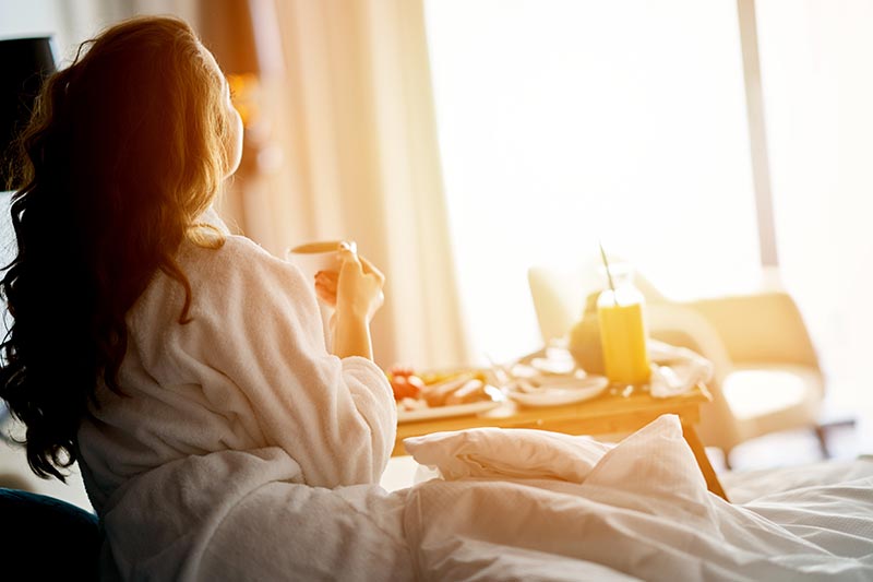 Eine Frau genießt Frühstück im Bett im Hotel