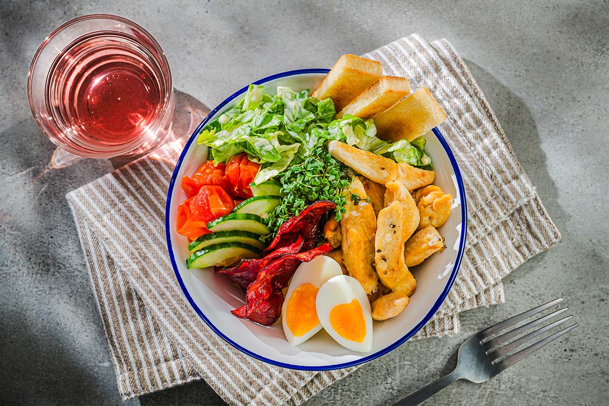 Bowl mit Kartoffelpüree, gebackenen Tomaten und Hähnchenbruststreifen ...